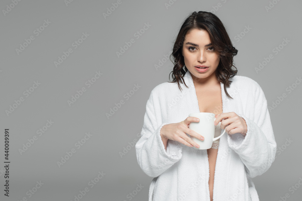 Woman in bathrobe holding cup isolated on grey Woman in bathrobe holding cup isolated on grey