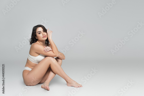 Pretty woman in lingerie sitting on grey background