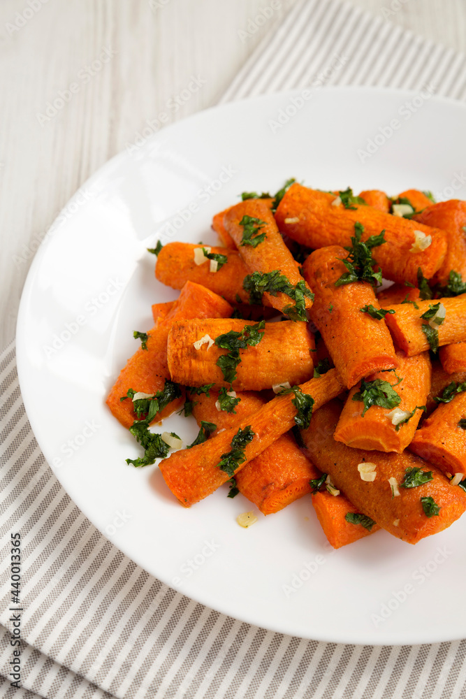 Homemade Roasted Carrots with Herbs on a white plate, side view. Homemade Roasted Carrots with Herbs on a white plate, side view.