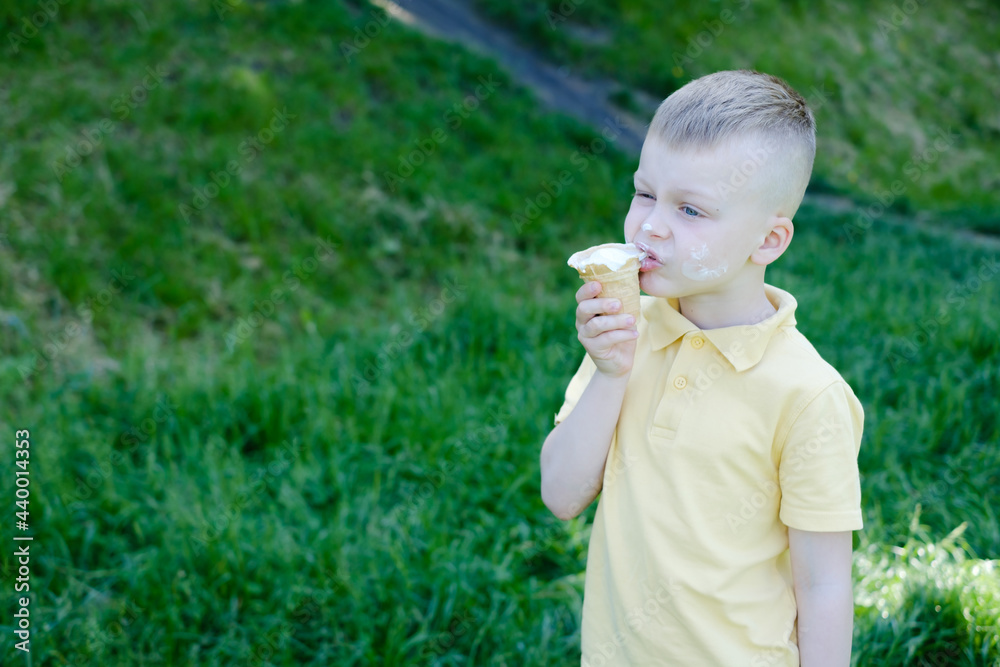 Boy eating ice cream with stains around his mouth. outdoors in the park Boy eating ice cream with stains around his mouth. outdoors in the park