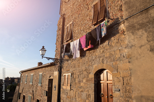Volterra, Tuscany, Italy. August 2020. On the facade of one of the characteristic houses of the historic center, clothes hanging in the evening sun. Characteristic glimpse of the village. © Massimo Parisi