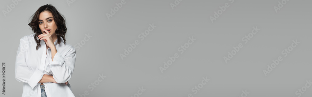 Pretty woman in shirt looking at camera isolated on grey, banner Pretty woman in shirt looking at camera isolated on grey, banner