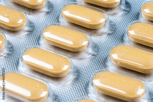 Macro shot pile of yellow tablets pill in blister packaging background. Aluminium foil blister pack. Pharmacy products. Medicine pills and drugs close up. Health care. Pills background photo