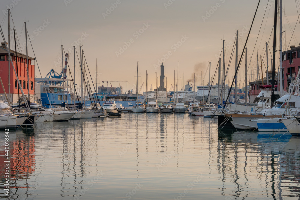 View of the old port of Genoa at sunset with boats and Lanterna lighthouse, Italy.