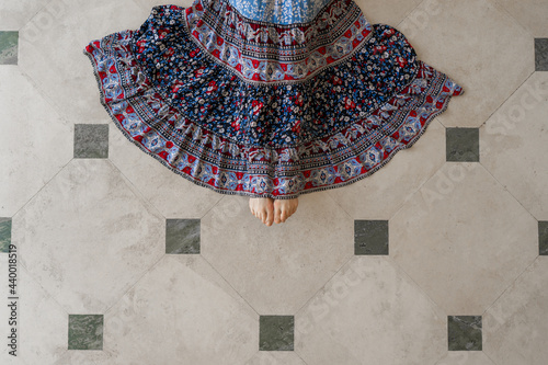Woman with blue dress on tile floor viewed from above