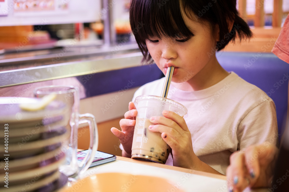 タピオカミルクティーを飲む小学生の女の子