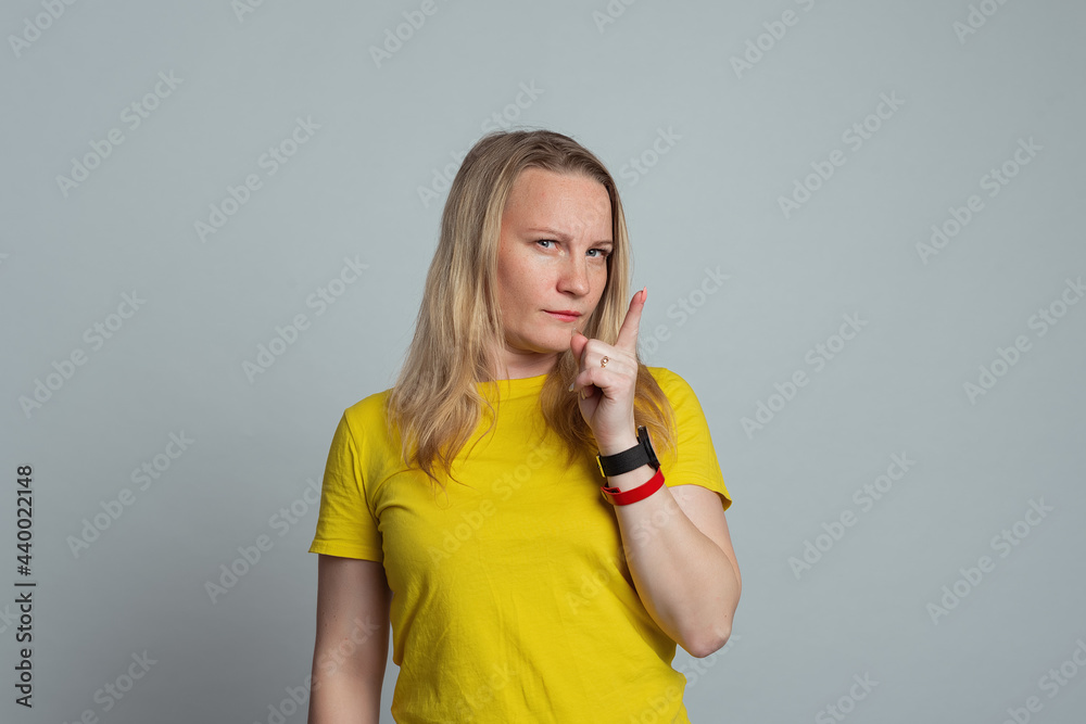 mature woman standing in thinking pose in casual yellow t shirt and looking thoughtful, front view mature woman standing in thinking pose in casual yellow t shirt and looking thoughtful, front view