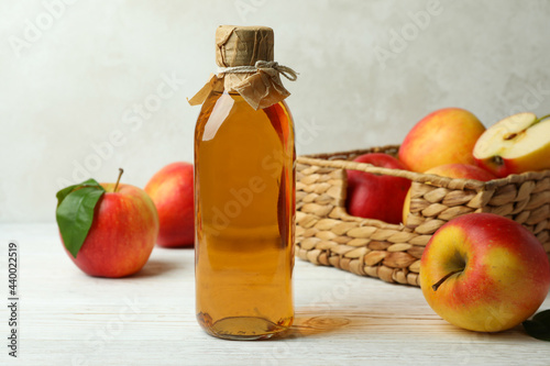 Homemade apple vinegar and ingredients on white wooden table