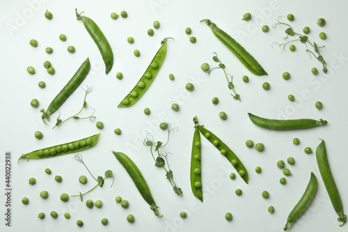 Green pea pods, seeds and twigs on white background