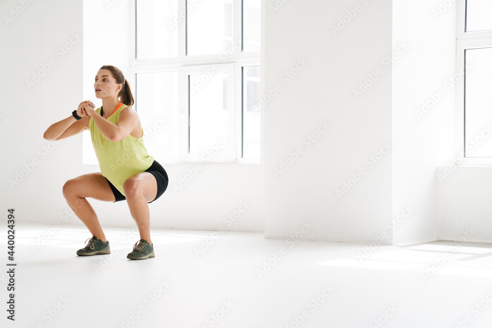 Fototapeta premium Young white sportswoman doing exercise while working out indoors