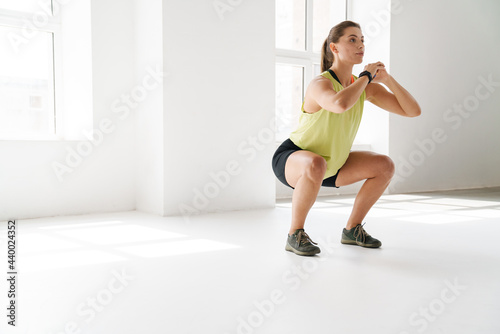 Young white sportswoman doing exercise while working out indoors