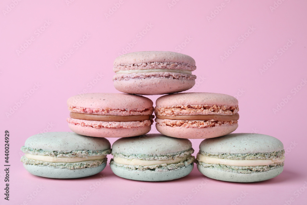 Pile of delicious colorful macarons on pink background