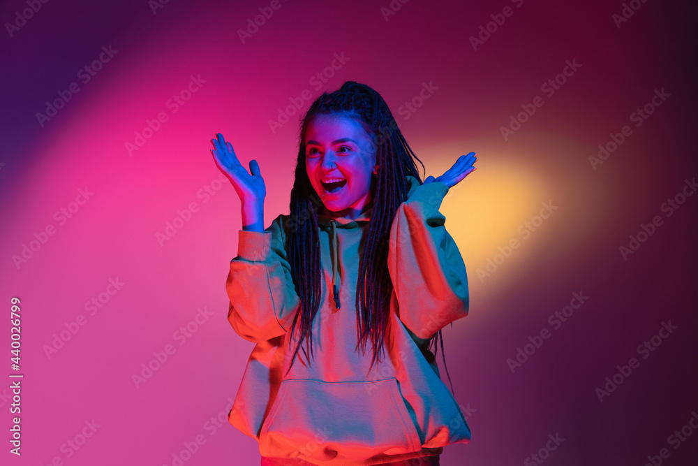 Young woman's portrait on gradient colors studio background in neon. Concept of human emotions.