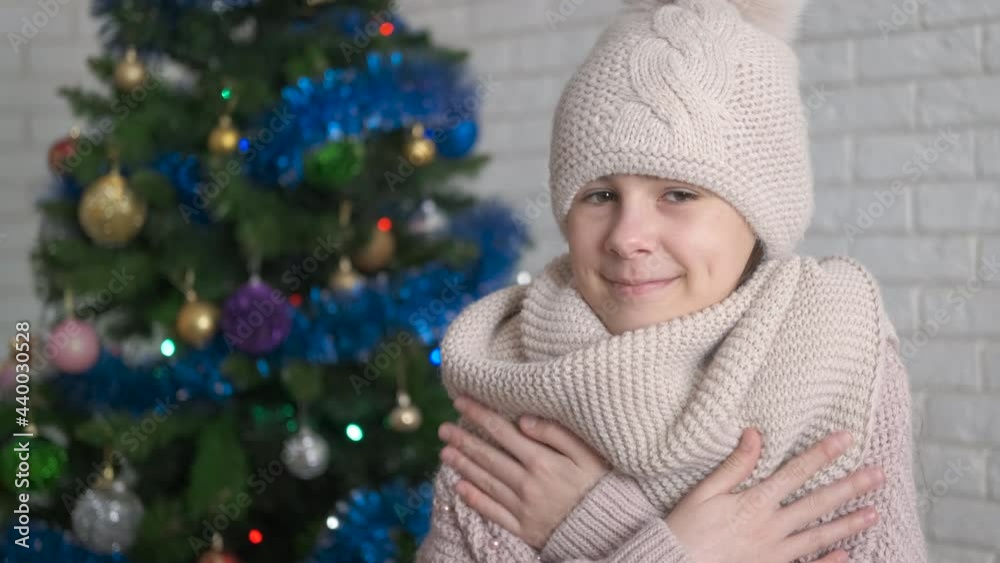 Get warm on new Year holiday. A view of a nice good looking teen in knitted clothes stay by the New Year tree. Get warm on new Year holiday. A view of a nice good looking teen in knitted clothes stay by the New Year tree.