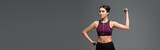 young woman in black sportswear training with dumbbells isolated on grey, banner.