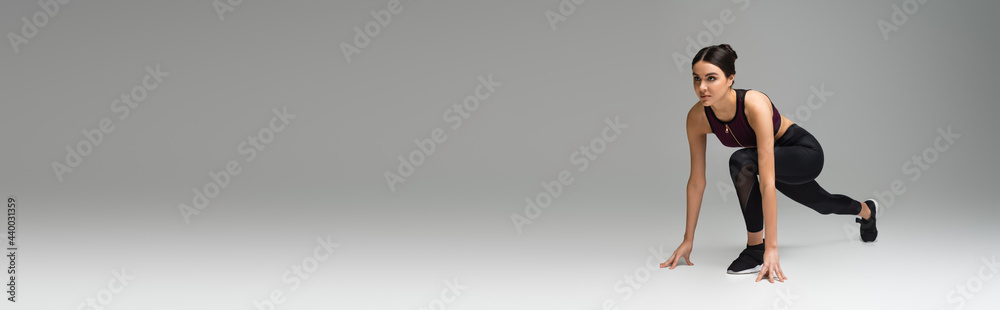sportswoman in low start position on grey background, banner. sportswoman in low start position on grey background, banner.