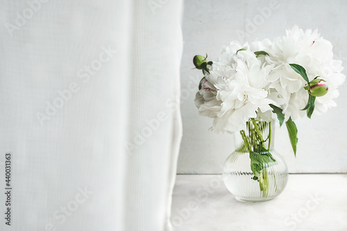 Fototapeta Naklejka Na Ścianę i Meble -  depth of field Bud of white wet peony in a stylish glass vase by the window. interior poster for printing, home decor, selective focus
