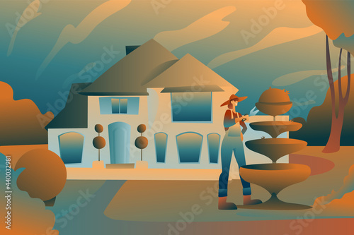 A woman cuts bushes with scissors, a gardener in a hat and overalls on the background of a country mansion. A house in nature with plants, sculptures from bushes, garden care.