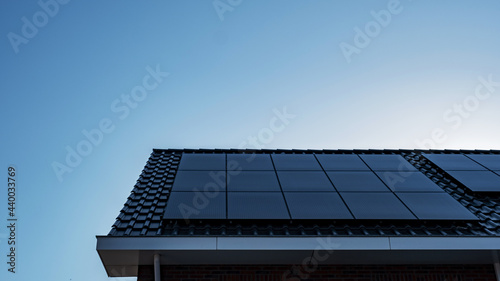 Newly build houses with solar panels attached on the roof against a sunny sky Close up of new building with black solar panels. Zonnepanelen, Zonne energie, Translation: Solar panel, , Sun Energy photo
