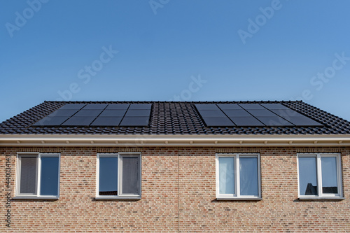 Newly build houses with solar panels attached on the roof against a sunny sky Close up of new building with black solar panels. Zonnepanelen, Zonne energie, Translation: Solar panel, , Sun Energy photo