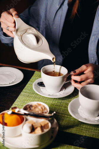 A woman with a cup of hot tea in her hands sits in the restaurant. The girl drinks aromatic tea. Enjoy the moment, take a break.