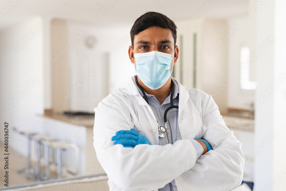 Portrait of hispanic male doctor wearing face mask standing with arms crossed looking to camera Portrait of hispanic male doctor wearing face mask standing with arms crossed looking to camera
