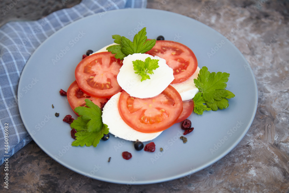 Italian caprese salad with sliced tomatoes, mozzarella, basil, olive oil on a blank plate. View from above. Italian caprese salad with sliced tomatoes, mozzarella, basil, olive oil on a blank plate. View from above.