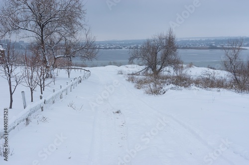 Snowy road leading down to frozen Dnipro river near the same name city in Ukraine at winter season