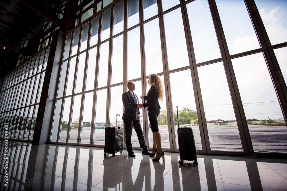 Two business people discussing in airport terminal while traveling on board.