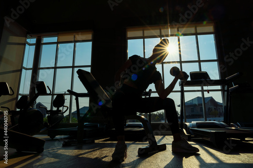 Silhouette, A young female sits up in a sports club. Beautiful young athletic woman doing sit-ups in a sports club.