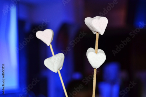white marshmallows in the shape of hearts on a blue background congratulate you on Valentine's Day. © Ann