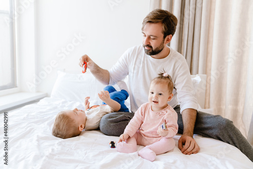 White bearded father playing with his children on bed at home