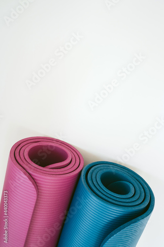 Pink and blue rolled mats for yoga, pilates or fitness isolated close up on white background. Professional equipment for sport training, workout at home or gym. Healthy lifestyle concept