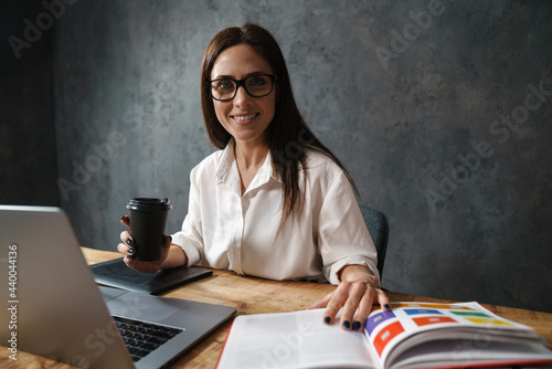 Mid aged brunette businesswoman in shirt sitting