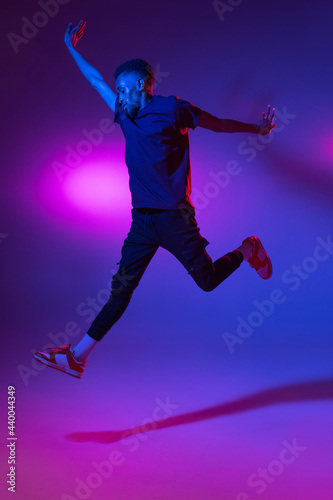 African-american young man's portrait on dark studio background in neon. Concept of human emotions, facial expression, youth, sales, ad. © master1305