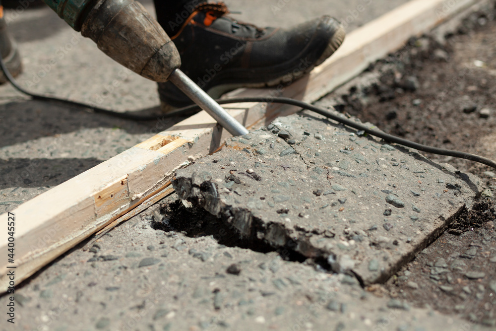 He removes the asphalt with a jackhammer. Removing the asphalt layer from the road. He removes the asphalt with a jackhammer. Removing the asphalt layer from the road.