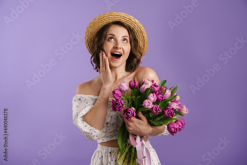 White surprised woman in hat exclaiming while posing with tulips