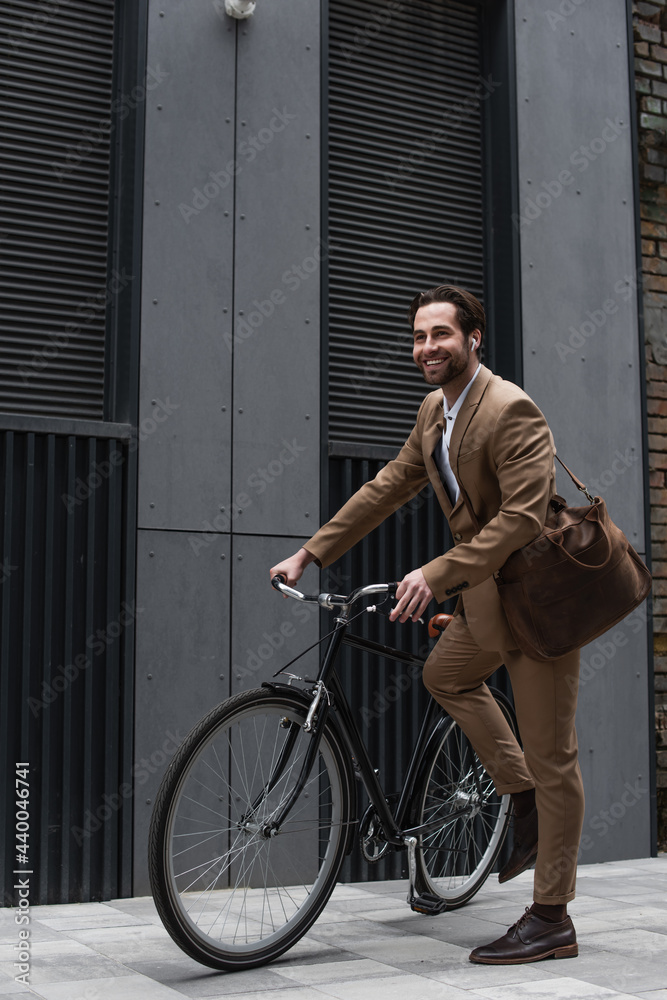 full length of happy businessman in earphones riding bicycle. full length of happy businessman in earphones riding bicycle.