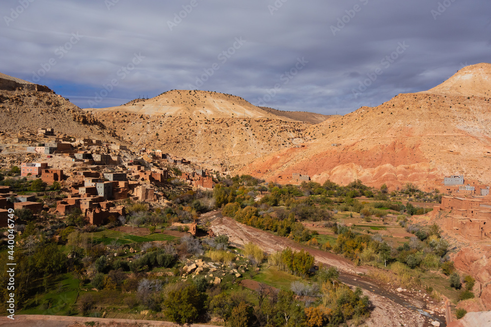 mudbrick village on the side of a hill in the High Atlas mountains with a cloudy blue sky