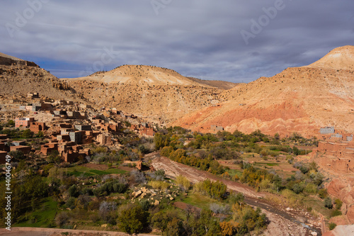 mudbrick village on the side of a hill in the High Atlas mountains with a cloudy blue sky
