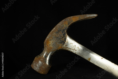 rusty hammer head and shaft with head down isolated on a black background