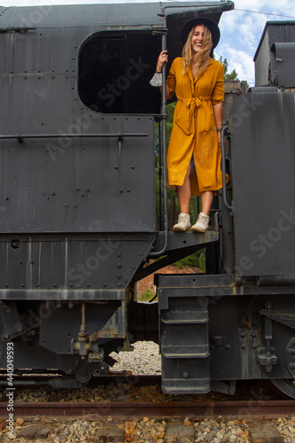 young Spanish blonde woman with a yellow dress and a black hat in an old train station
