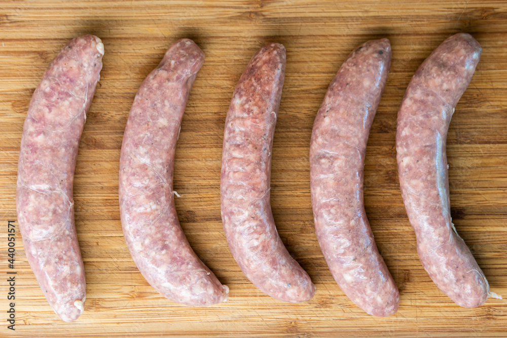Fresh raw Italian sausages on a wooden kitchen board close up shot top view no people Fresh raw Italian sausages on a wooden kitchen board close up shot top view no people