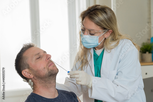 Doctor testing adult man for coronavirus infection performing nasal swab, PCR or rapid COVID-19 test