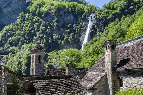 The tradtional stone houses with church tower in the beautiful village of Foroglio and the famouse waterfall at the background, Ticino, Switzerland photo