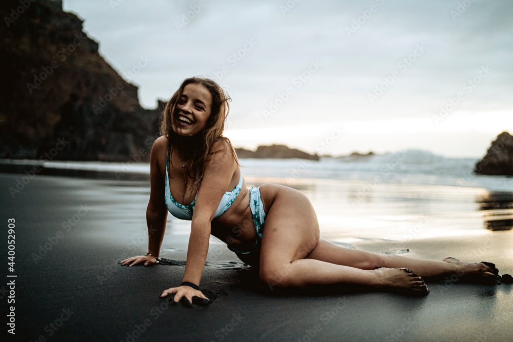 Chica veraniega guapa en una playa de arena negra durante el atardecer luciendo su bikini de moda Chica veraniega guapa en una playa de arena negra durante el atardecer luciendo su bikini de moda