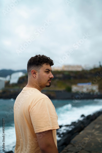 Chico moreno posando con fondo de acantilado y mar