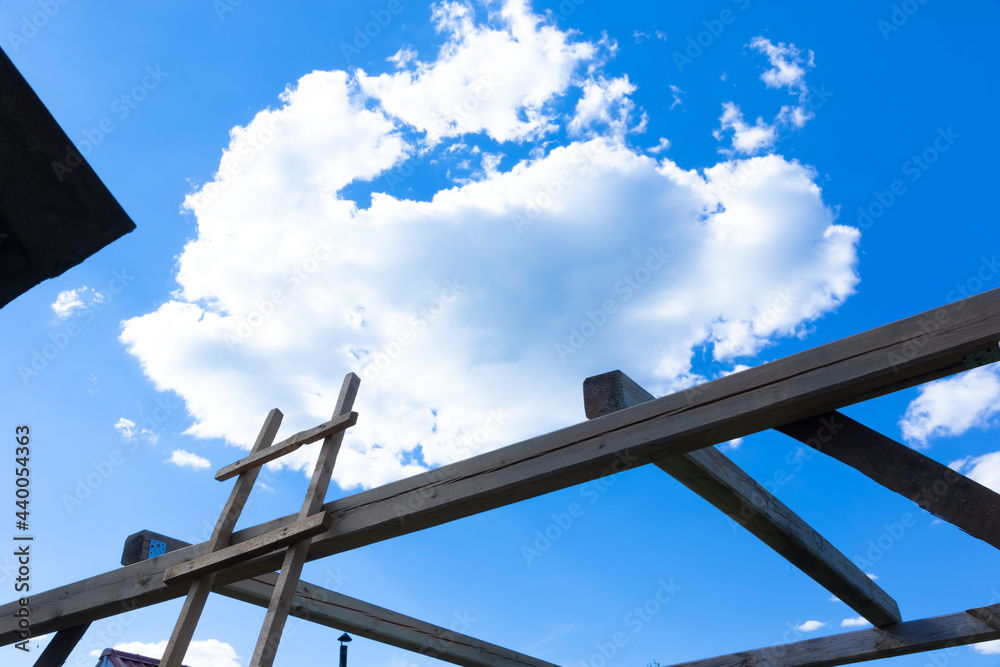 Against the background of a timber frame building, a blue sky with white clouds on a bright sunny summer day. Rural landscape. Against the background of a timber frame building, a blue sky with white clouds on a bright sunny summer day. Rural landscape.