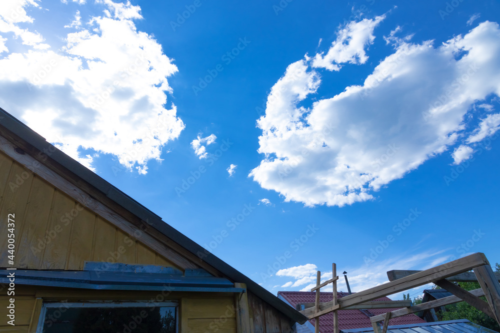 Against the background of a timber frame building, a blue sky with white clouds on a bright sunny summer day. Rural landscape.