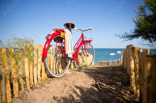 Bord de mer et vieux vélo rouge à l'entrée d'une plage.